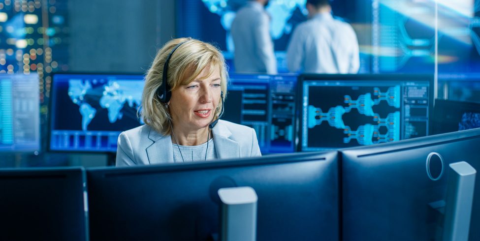 Sales woman with headset in front of computer monitors